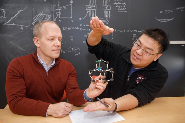Image 1: Chris Laumann (left) and Norman Yao explain high-pressure hydride superconductor research. Credit: Kris Snibbe/Harvard Staff Photographer Image 2: An artist’s rendering of nitrogen vacancy centers in a diamond anvil cell, which can detect the expulsion of magnetic fields by a high-pressure superconductor. Credit: Ella Marushchenko